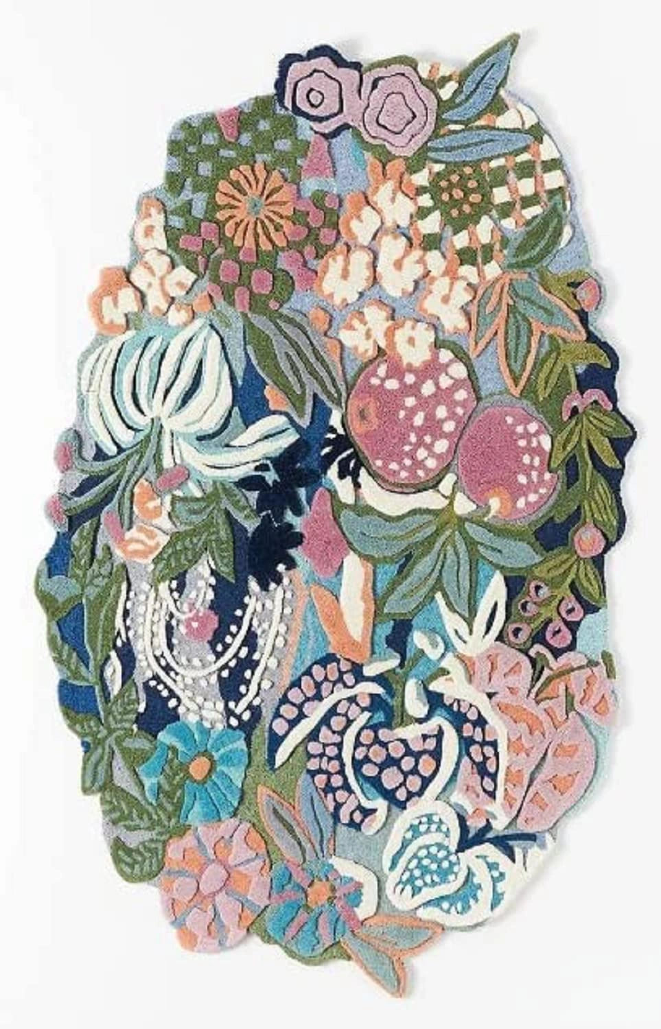 A decorative patchwork rug featuring a dense, colorful floral and botanical pattern with pomegranates, leaves, and abstract shapes in pink, blue, green, purple, and cream on a white background.