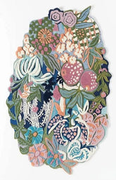 A decorative patchwork rug featuring a dense, colorful floral and botanical pattern with pomegranates, leaves, and abstract shapes in pink, blue, green, purple, and cream on a white background.