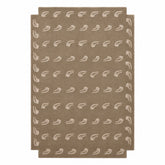 A rectangular area rug in a warm taupe-brown color, featuring a repeating pattern of small white stylized leaf or feather motifs and a matching white border.