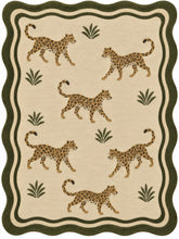 A rectangular area rug with a scalloped border, featuring a repeating pattern of walking cheetahs and small palm-like plants on a warm beige background.