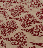 Beige rug with ornate red damask pattern featuring intricate floral and swirl details