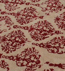 Beige rug with ornate red damask pattern featuring intricate floral and swirl details