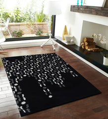 Modern black area rug with abstract white and gray pattern on wooden floor in bright living room