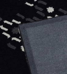 Black modern rug with white and gray abstract pattern and blue fabric edge corner