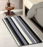 Black and white striped hand-tufted wool runner rug beside a bed on a tiled floor
