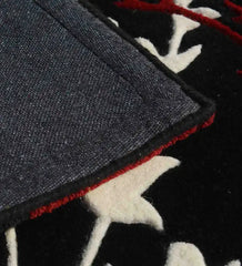Close-up of black floral hand-tufted runner rug with white and red details