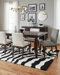 Black and ivory zebra pattern hand-tufted area rug styled in a dining room, adding a bold and modern statement