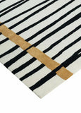 Modern area rug with black and white vertical stripes and a horizontal golden accent line