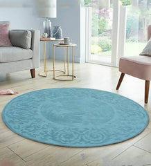 Round blue hand-tufted wool rug with intricate traditional patterns in a bright living room