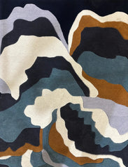 Blue modern abstract rug with wavy patterns in blue, cream, grey, black, and brown tones