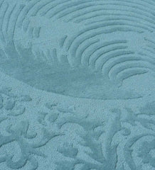 Close-up of blue traditional hand-tufted round rug with intricate textured pattern