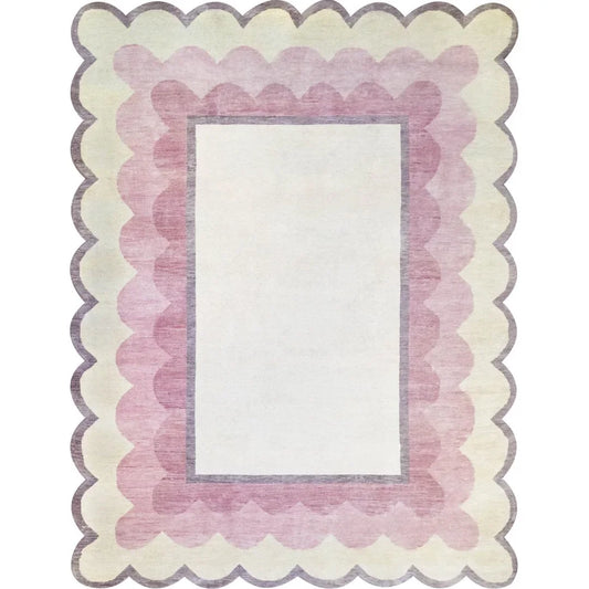 Hand-knotted blush pink rug with scalloped border, crafted from wool.