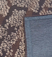Close-up of brown and beige abstract textured rug with floral pattern and blue edge backing