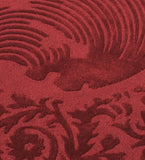 Close-up of burgundy traditional ornate round rug with intricate floral and swirl patterns