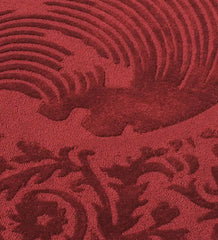 Close-up of burgundy traditional ornate round rug with intricate floral and swirl patterns