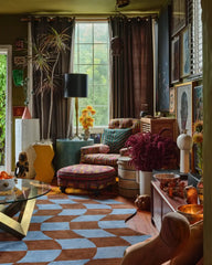Cozy living room with a blue and brown checkered rug, patterned armchair, and eclectic decor