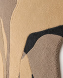 Close-up of a textured rug with geometric pattern in beige, brown, and black.