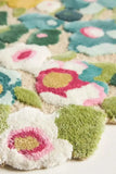 Close-up of colorful handwoven floral rug with textured green, white, pink, and blue blooms by Mannat Rugs