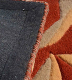 Close-up of colorful abstract hand-tufted runner rug with red, beige, and orange geometric patterns, detailed edge binding
