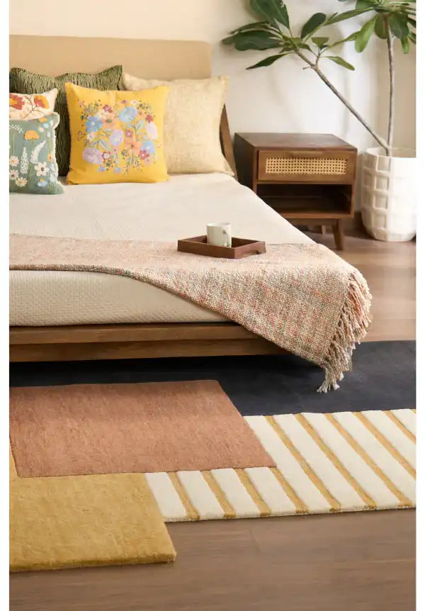 Artistic geometric rug with mustard, rust, cream, and black blocks.