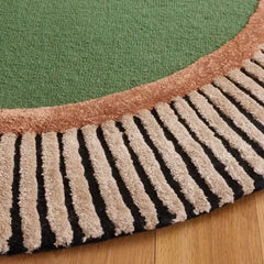 Close-up of Mannat Rugs handwoven oval rug with green center, brown border, and striped fringe on wood floor