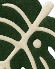 Handcrafted green leaf-shaped rug with cream detailing.