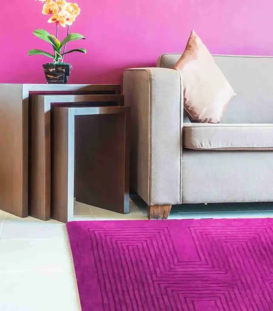 Magenta geometric wool rug in modern living room with beige sofa, nesting tables, orchid plant