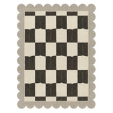 Checkered pattern rug with scalloped edge on a white background