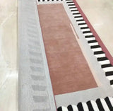 Modern color block rug with earth tones, black and white stripes, and soft textures on marble floor