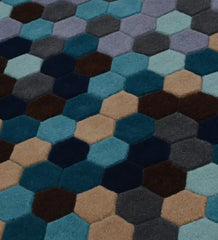 Close-up of modern geometric hexagon rug with gradient shades of blue, gray, brown, and beige