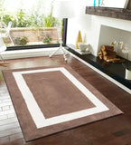 Hand tufted solid wool rug in brown and white rectangular design on dark hardwood floor in modern living room
