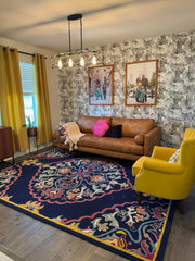 Luxury handwoven navy blue rug with intricate floral patterns in a stylish living room with yellow curtains and armchair