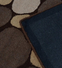 Close-up of a wool rug with a neutral pebble pattern in beige and brown tones, corner flipped over