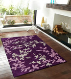Purple floral vine area rug on wooden floor in modern living room with fireplace and large window