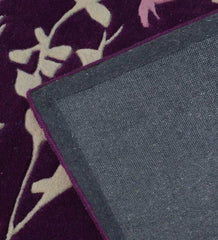Close-up of purple floral vine rug with beige flower patterns and gray woven backing