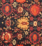 Close-up of a red and black vintage handwoven rug with intricate floral and geometric patterns