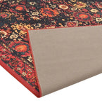 Close-up of a red vintage floral rug with folded corner showing beige non-slip backing, luxury handwoven design
