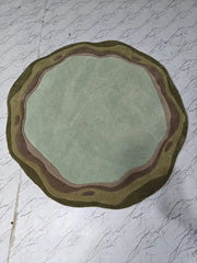 Round sage green and earthy tone handcrafted rug on white marble floor, luxury home decor