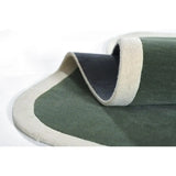 Close-up of folded elegant sage green rug with cream border and dark underside on white background