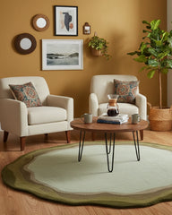 Living room with sage green round area rug, two beige armchairs, wooden coffee table, and earth tone decor