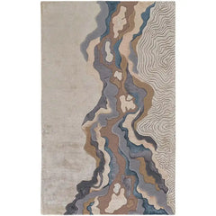 Hand-tufted luxury rug with abstract ripple and contour line design in neutral browns, blues, and grays