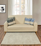 Minimalist beige sofa with patterned cushions in front of window, neutral taupe rug on wooden floor