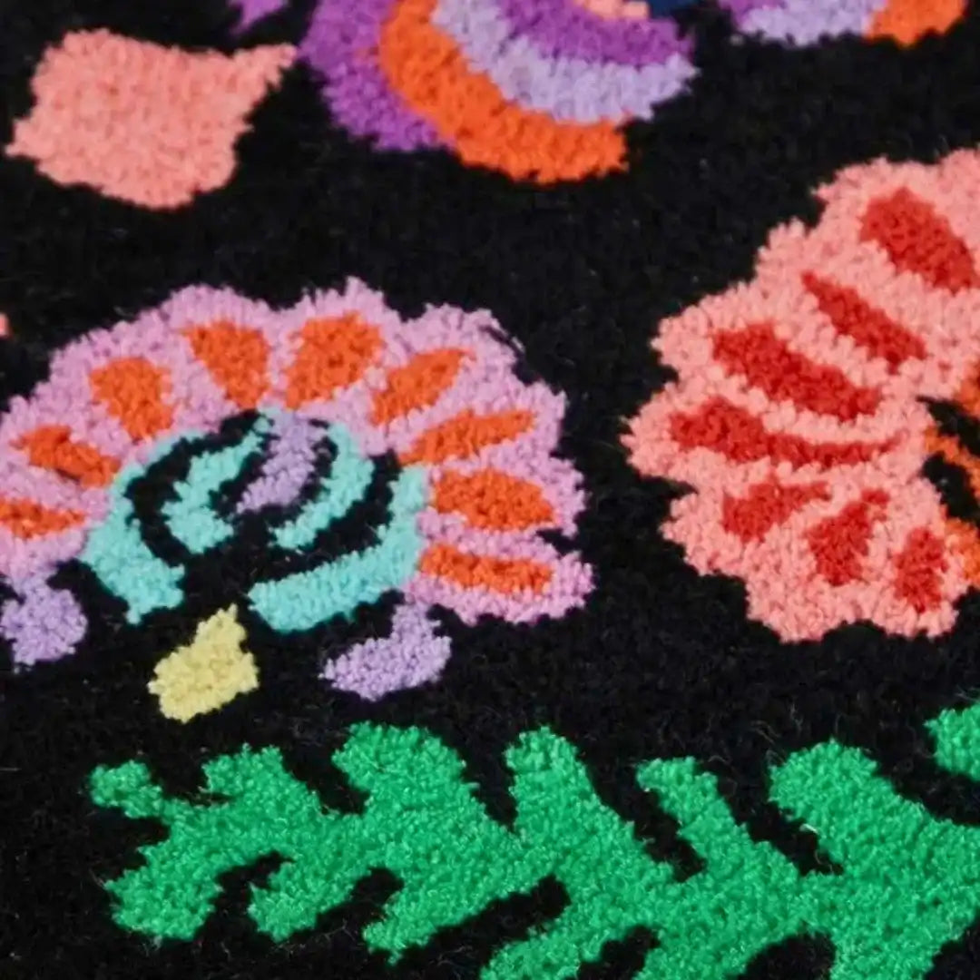 Colorful floral patterned area rug with green leaves and bright flowers on black background