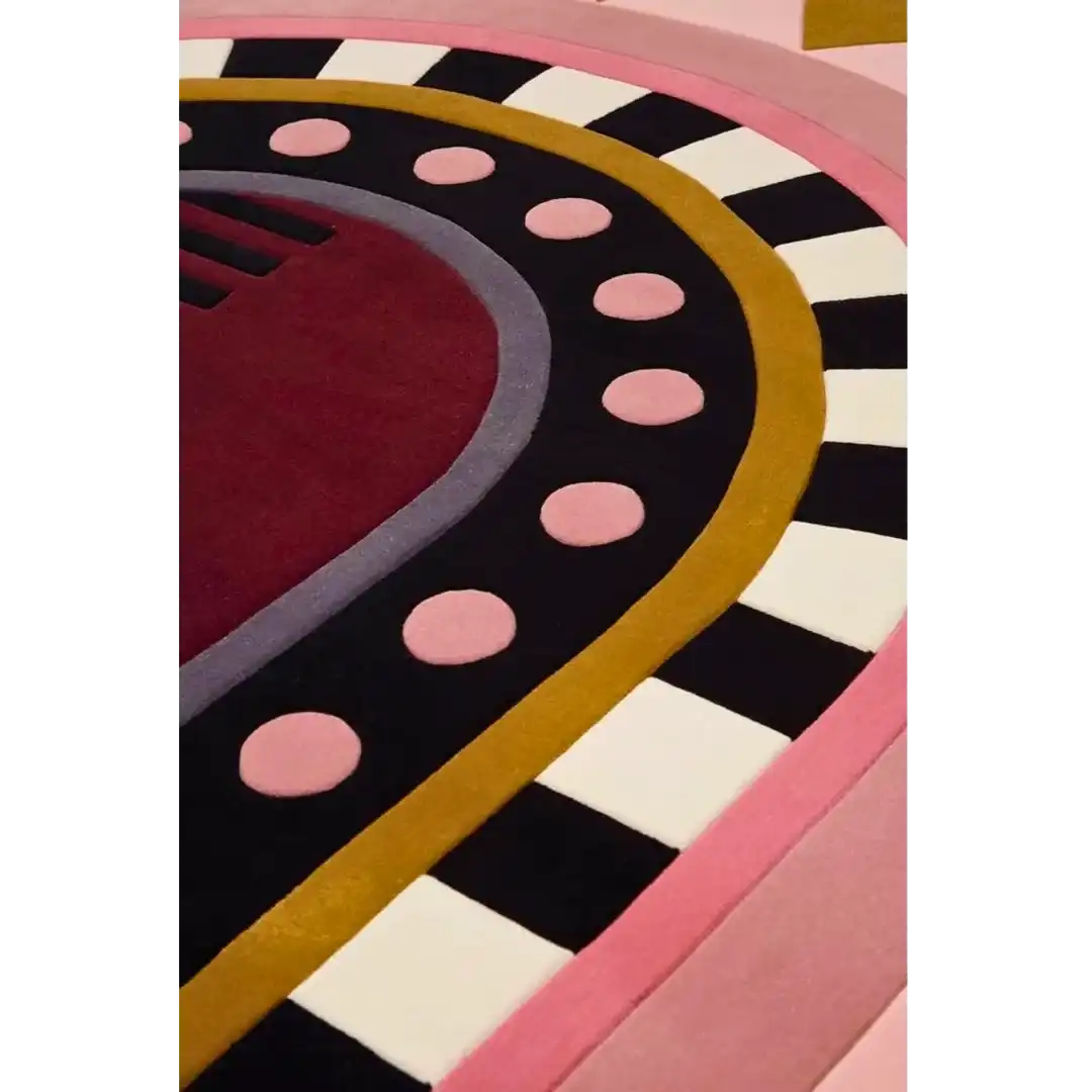 Close-up of a luxury handwoven rug with geometric patterns in burgundy, pink, black, white, and gold colors