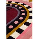 Close-up of a luxury handwoven rug with geometric patterns in burgundy, pink, black, white, and gold colors