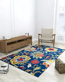 Living room with colorful floral pattern rug on light floor, wooden console table, and woven armchair
