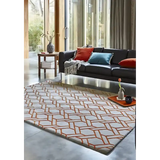 Modern living room with geometric patterned luxury area rug, black sofa with colorful cushions, and large glass windows