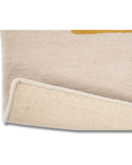 Close-up of a beige luxury handwoven rug with folded corner showing textured cotton backing and subtle mustard accent