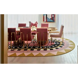 Luxury dining room with gold and pink chairs around a round gold table on a colorful geometric area rug