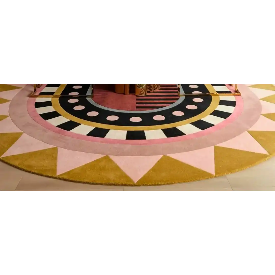 Round luxury rug with geometric design featuring pink, yellow, black, and white patterns on hardwood floor